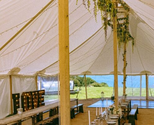 Inside our Sailcloth Marquee showing Ladder Truss systemdecorated with foilage shoing our Rustic tables and LOVE sign