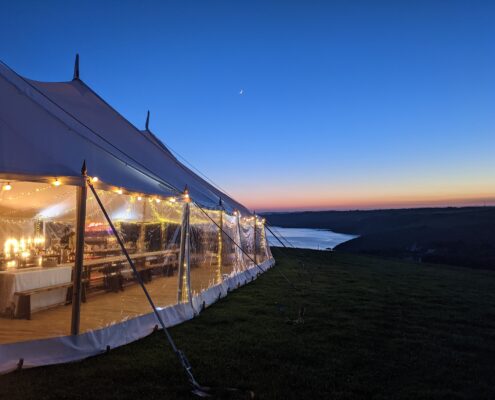 Special image of our 12x24m Celeste Sailcloth Marquee at Night with Sea Views at Sunset